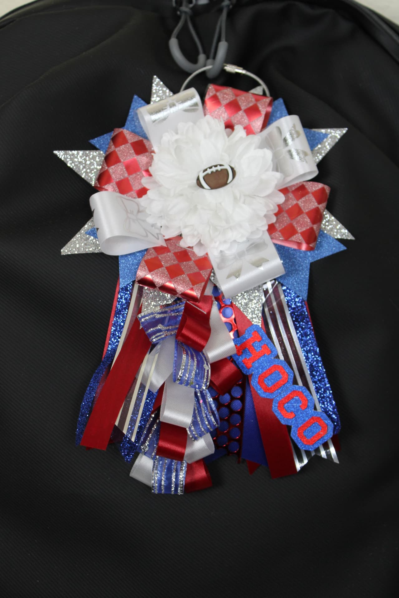 Mini homecoming mum keychain on a bag with a football charm