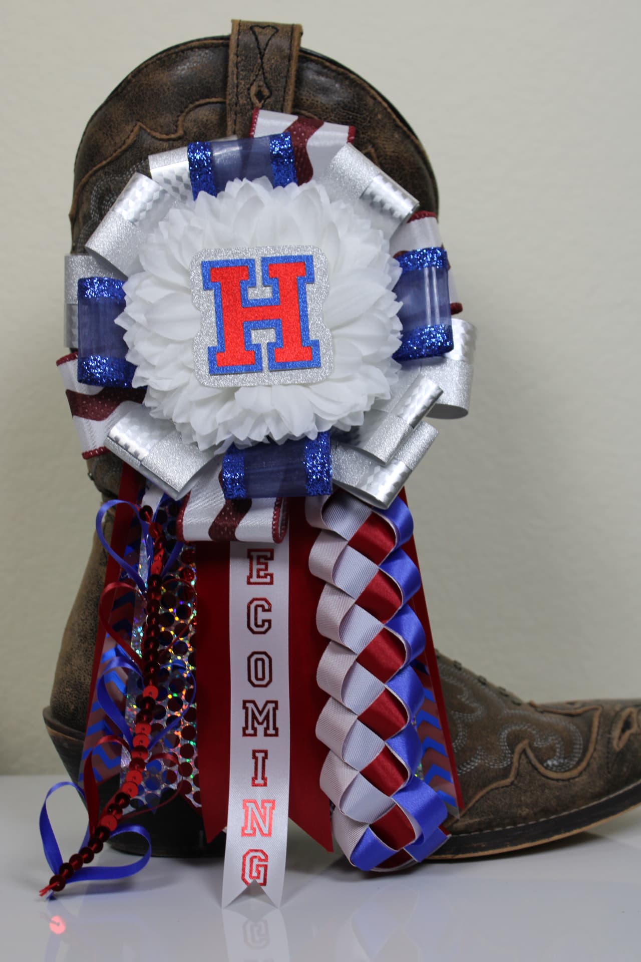 Homecoming mum on a cowboy boot with red, white and blue ribbons